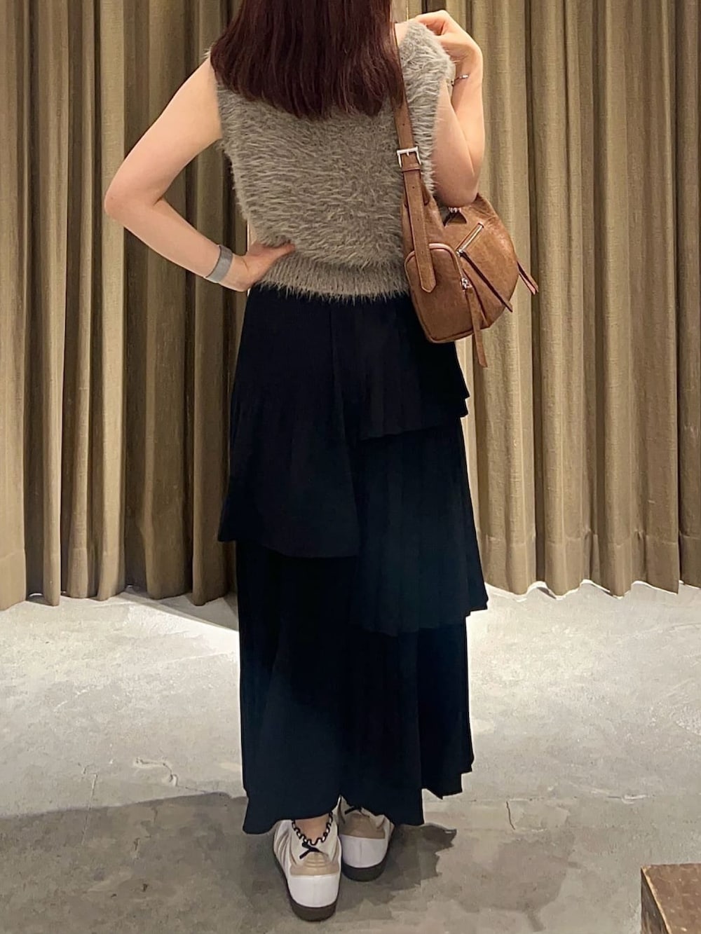 ブラウン系のベスト、ブラック系のスカート、ブラウン系のハンドバッグを着用したレディースの秋コーディネートの2枚目の写真