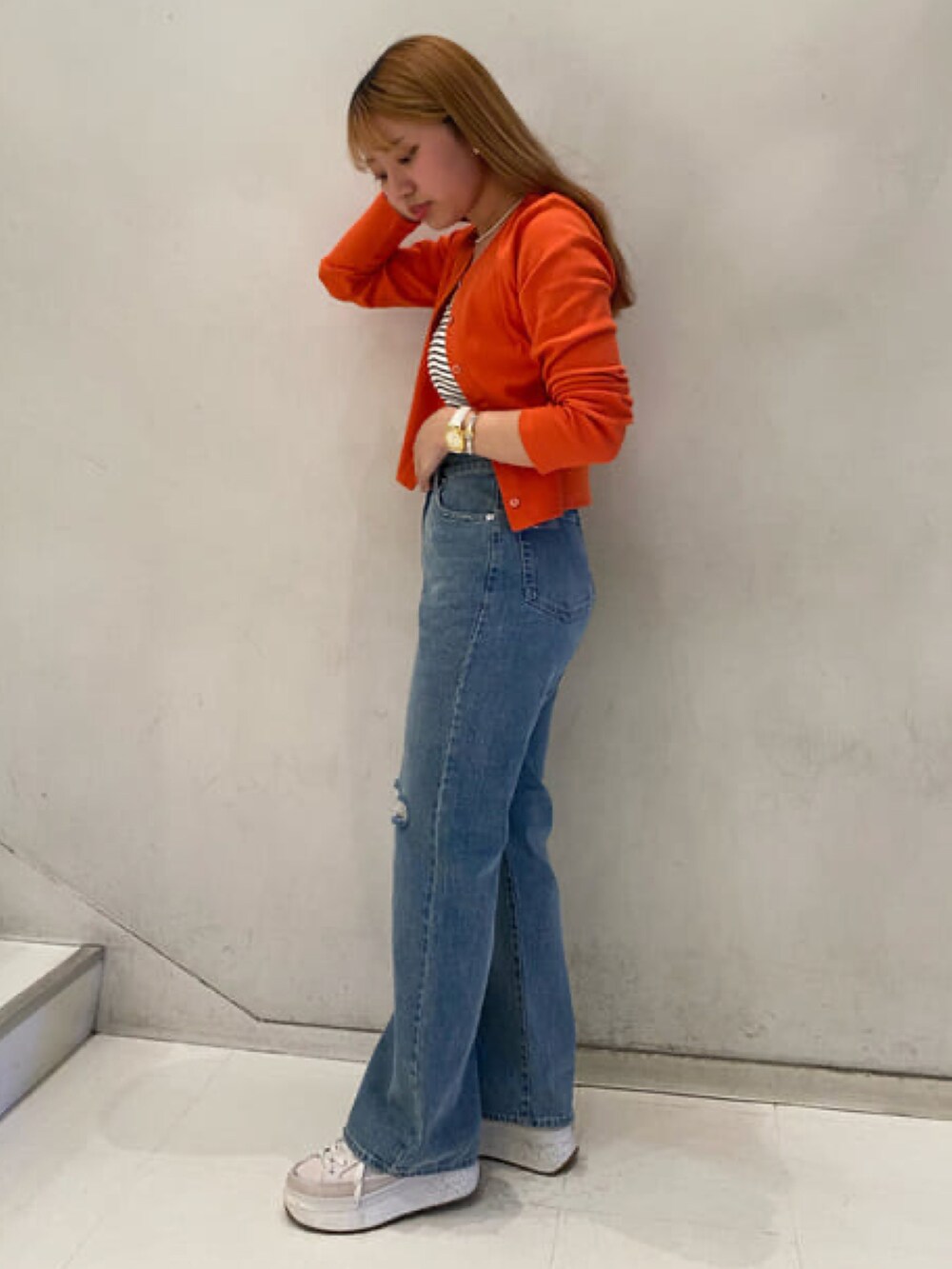 オレンジ系のカーディガン/ボレロ、ホワイト系のキャミソール、ブルー系のデニムパンツを着用したレディースの春コーディネートの2枚目の写真