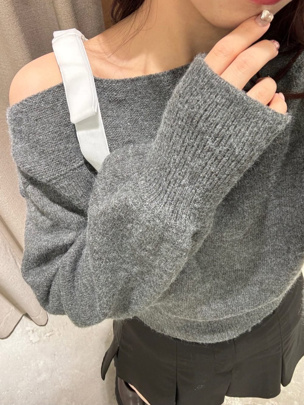 グレー系のニット/セーター、ホワイト系のショルダーバッグ、ブラック系のスカートを着用したレディースの冬コーディネートの3枚目の写真