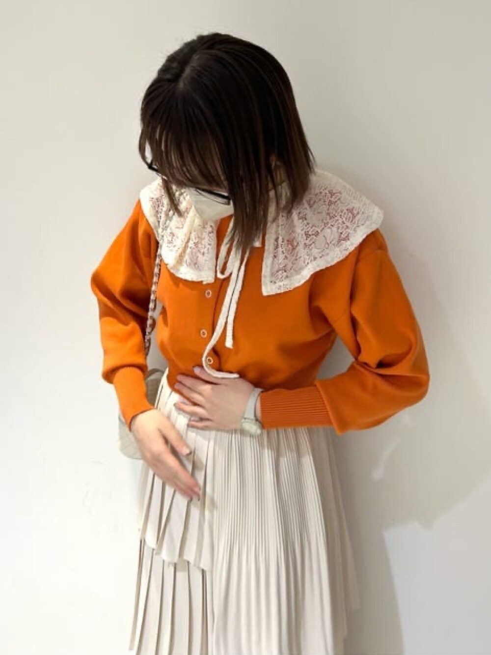 オレンジ系のカーディガン/ボレロ、ホワイト系のスカート、ホワイト系のショルダーバッグを着用したレディースの春コーディネートの2枚目の写真
