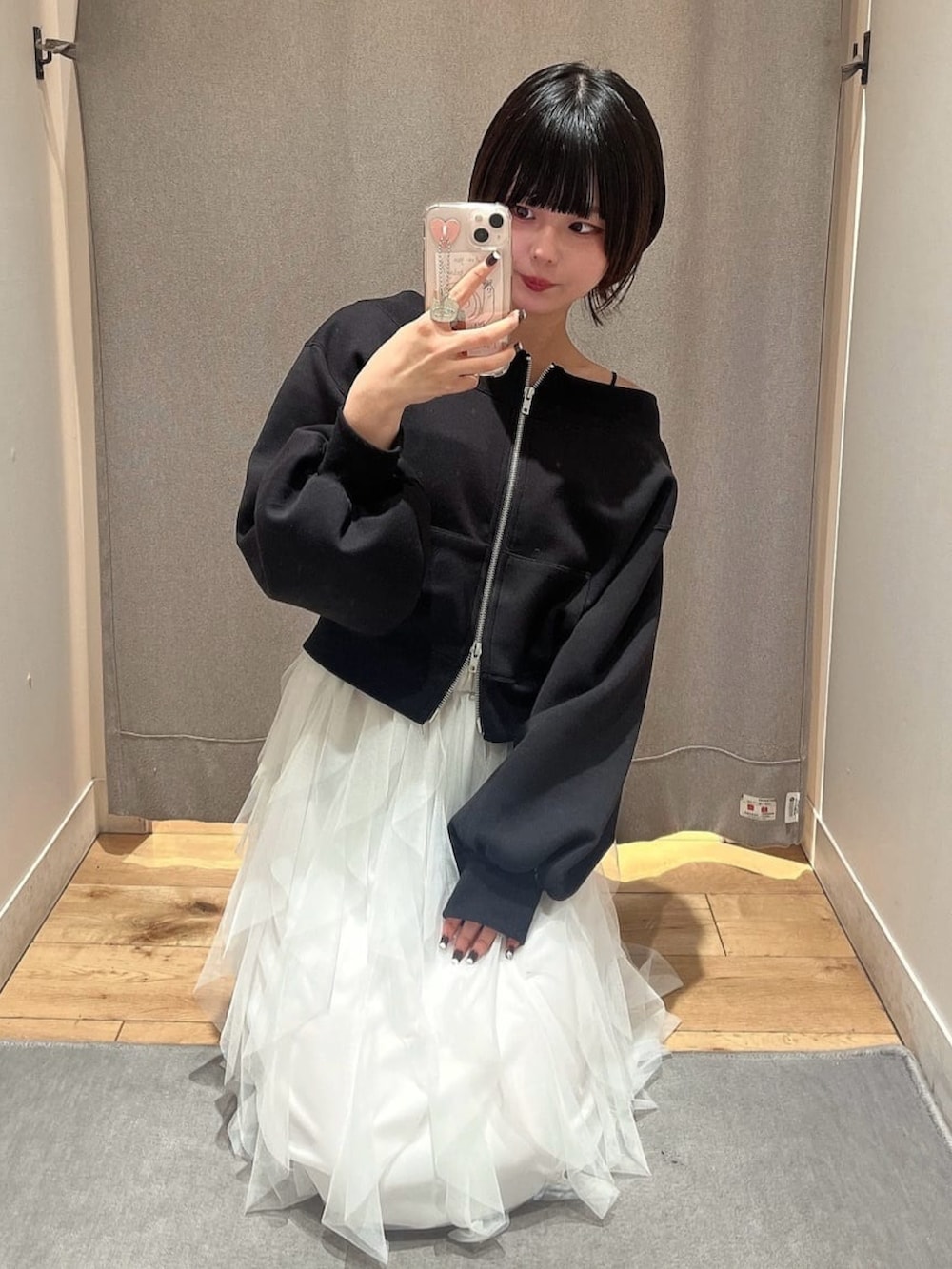 ブラック系のスウェット、ホワイト系のスカート、ブラック系のパンプスを着用したレディースの冬コーディネートの2枚目の写真