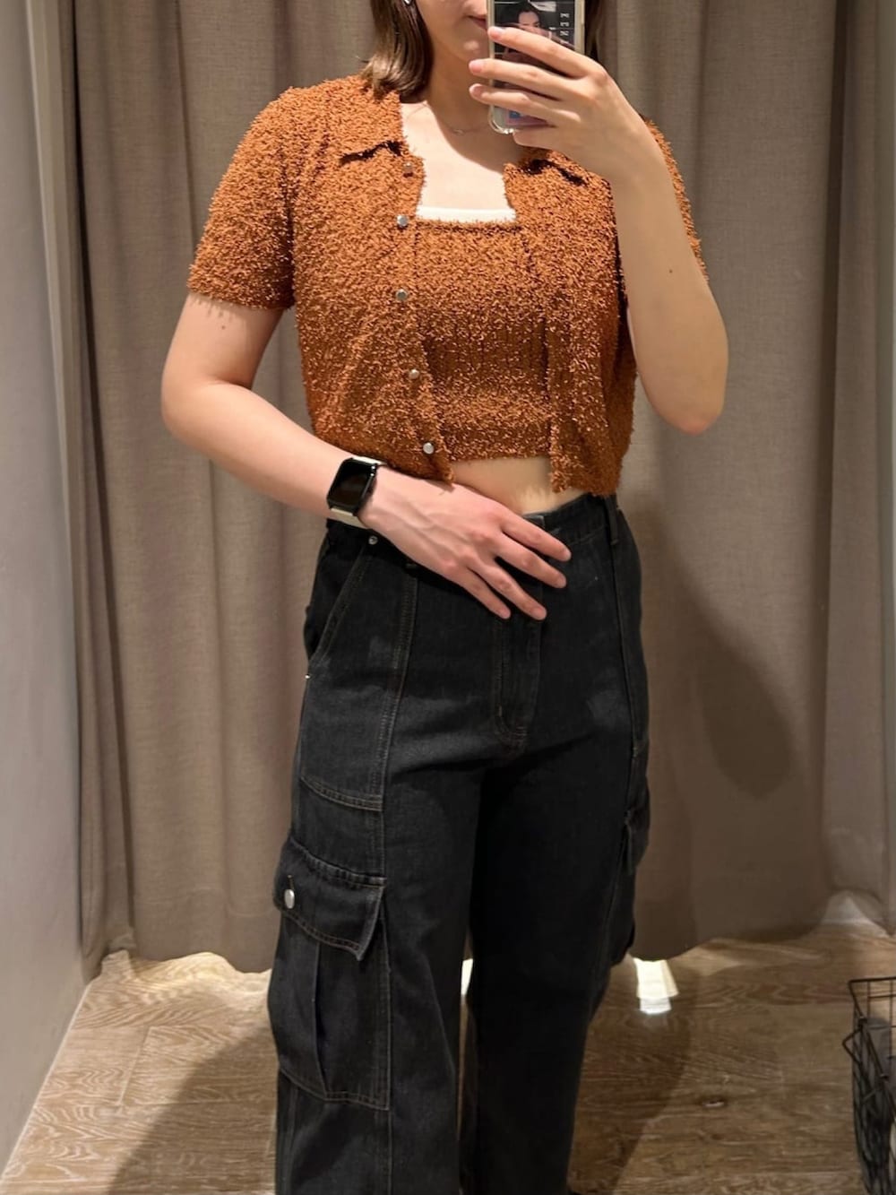 オレンジ系のニット/セーター、グレー系のデニムパンツ、ブラック系のハンドバッグを着用したレディースの夏コーディネートの2枚目の写真