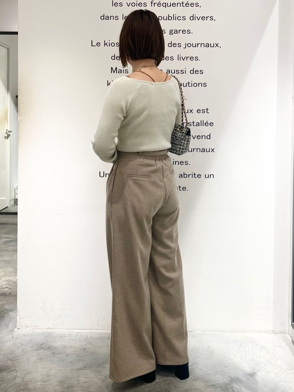 ホワイト系のニット/セーター、ベージュ系のスラックスを着用したレディースの冬コーディネートの2枚目の写真