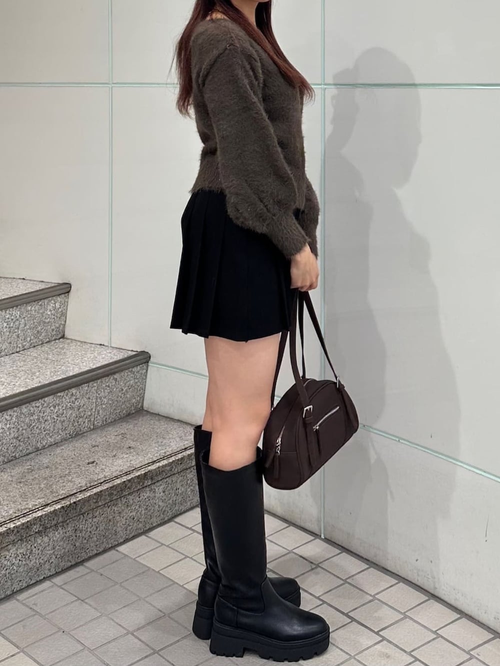 ブラウン系のニット/セーター、ブラック系のスカートを着用したレディースの秋コーディネートの2枚目の写真