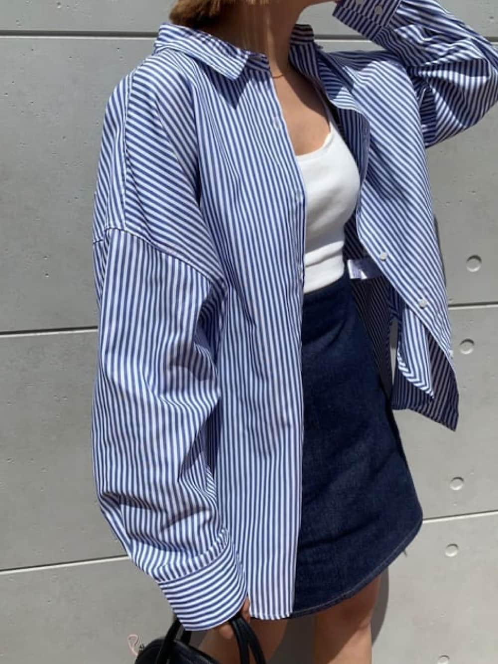 ブルー系のシャツ/ブラウス、ブルー系のデニムスカート、ブラック系のブーツを着用したレディースの春コーディネートの2枚目の写真