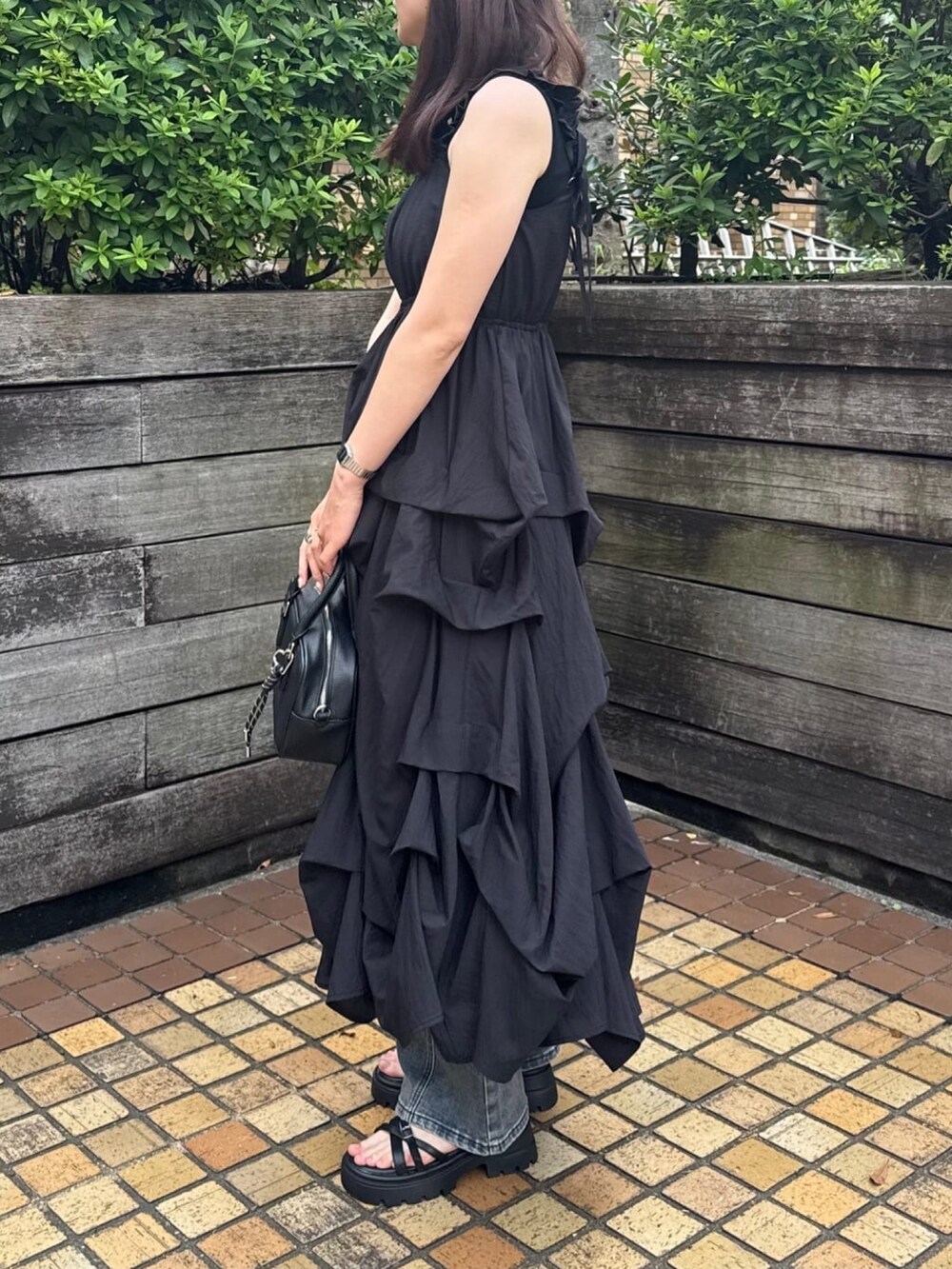 ブラック系のワンピース、ブルー系のデニムパンツ、ブラック系のボストンバッグを着用したレディースの夏コーディネートの2枚目の写真