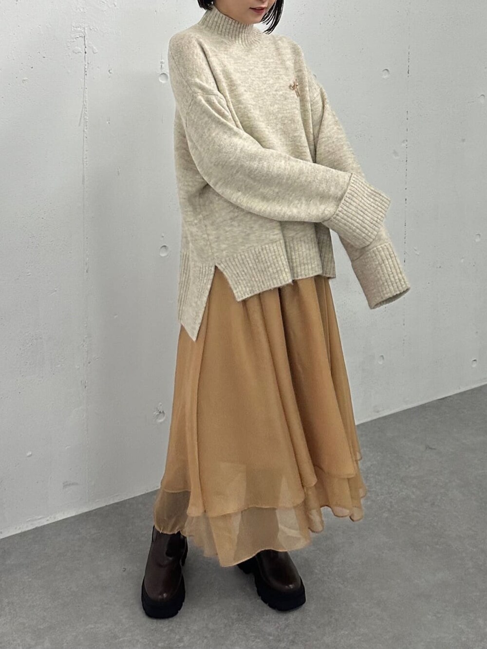 ホワイト系のニット/セーター、ブラウン系のスカート、ブラウン系のブーツを着用したレディースの冬コーディネートの2枚目の写真