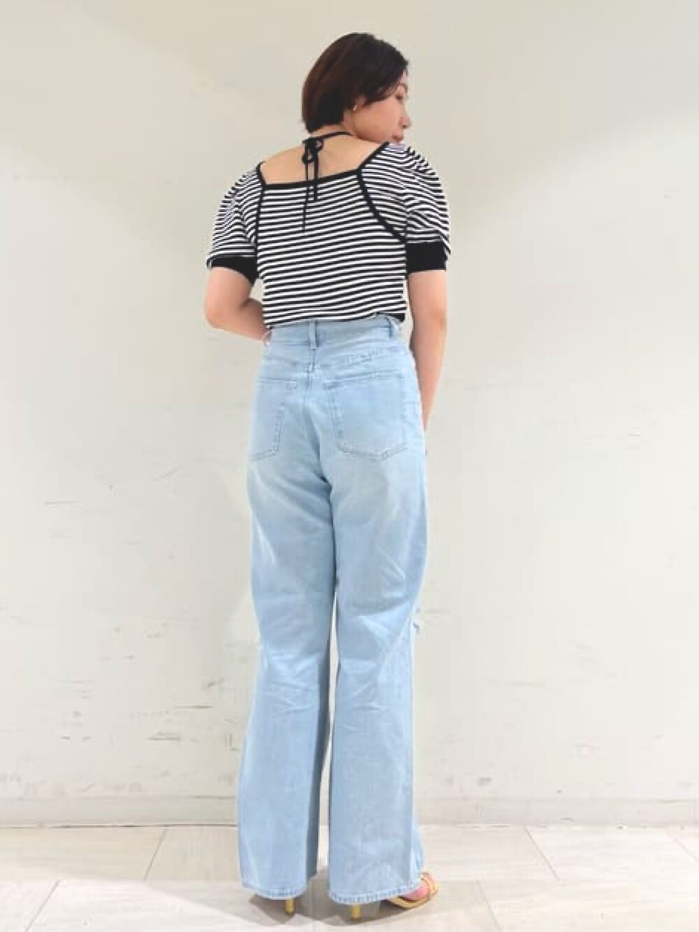 ホワイト系のニット/セーター、ブルー系のデニムパンツ、イエロー系のサンダルを着用したレディースの春コーディネートの2枚目の写真