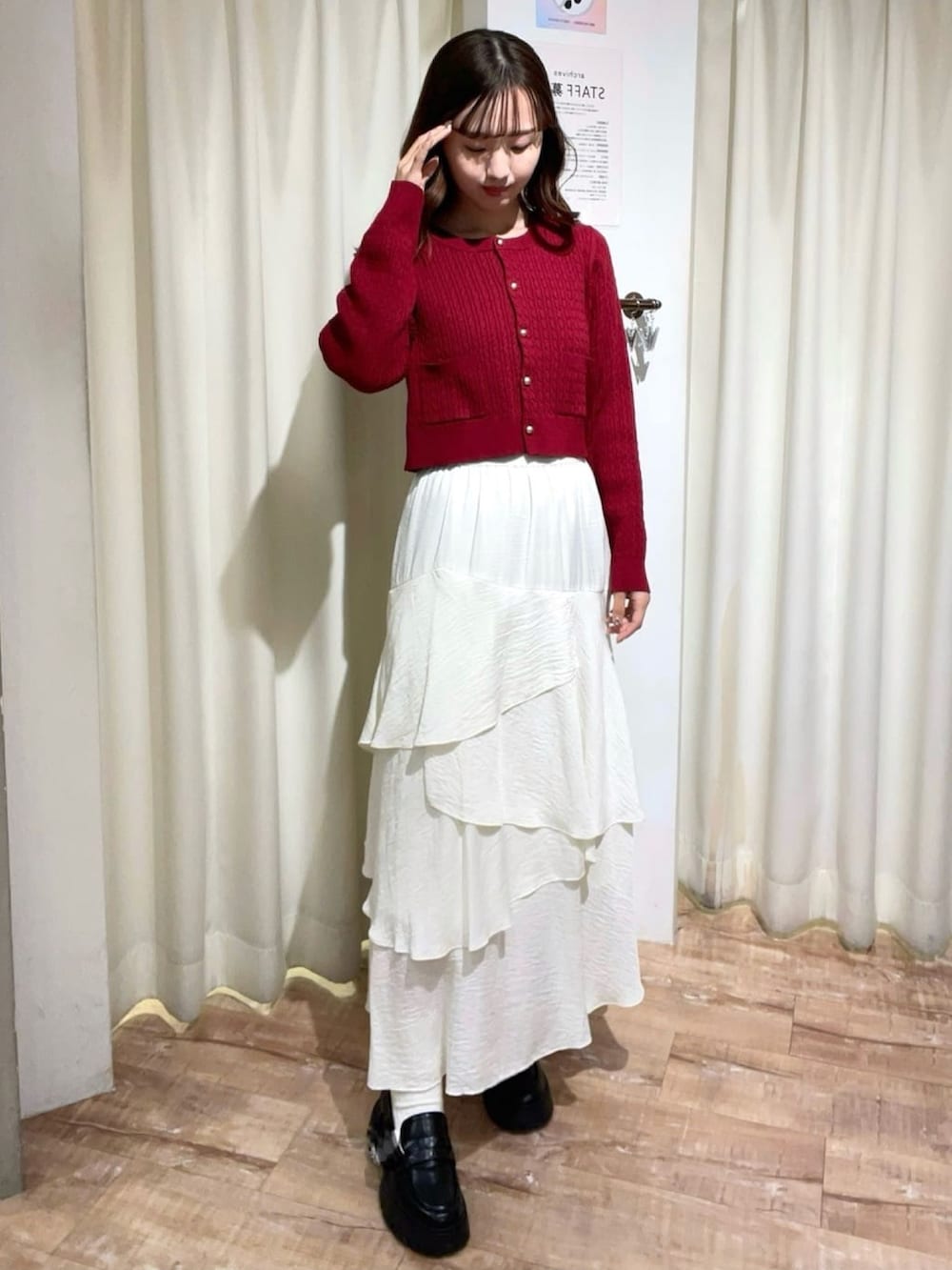 レッド系のニット/セーター、ホワイト系のスカート、ホワイト系のマフラーを着用したレディースの冬コーディネートの2枚目の写真