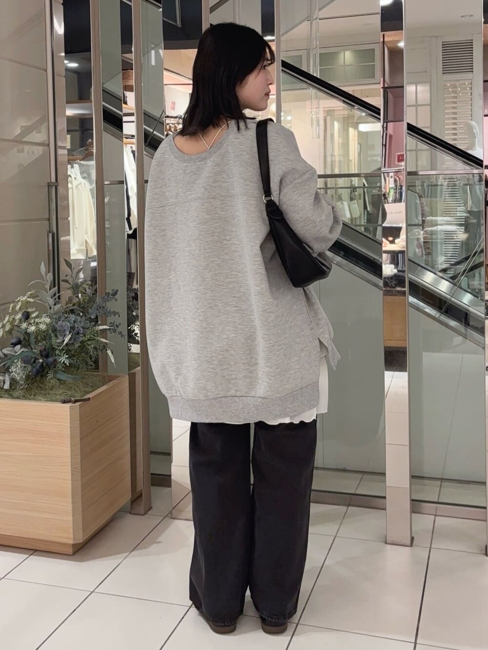 グレー系のスウェット、ホワイト系のスカート、ブラック系のデニムパンツを着用したレディースの冬コーディネートの2枚目の写真