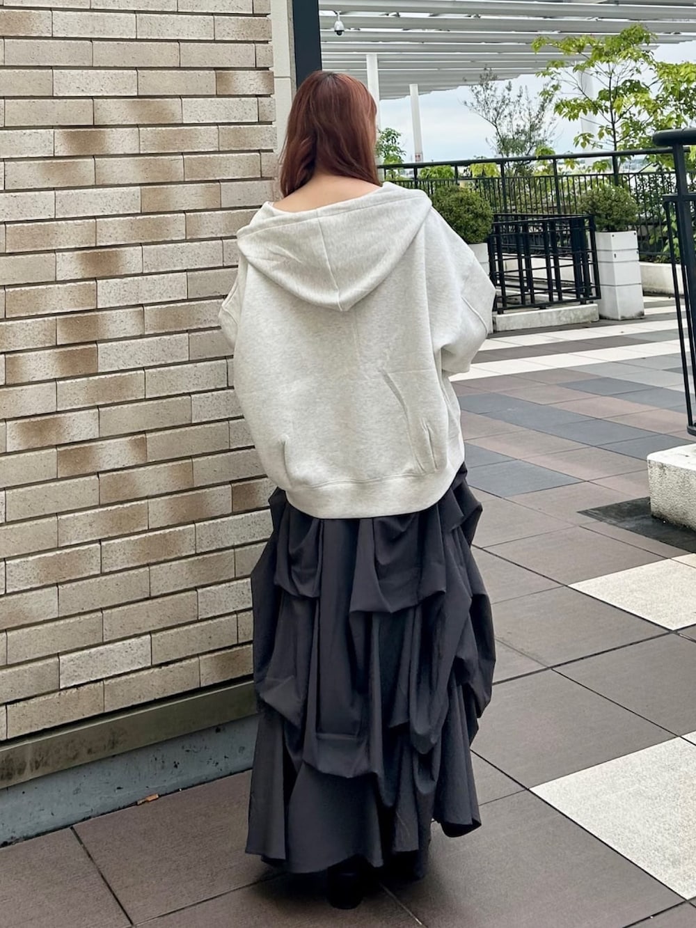 グレー系のスカート、ブラック系のショルダーバッグ、ベージュ系のパーカーを着用したレディースの秋コーディネートの2枚目の写真