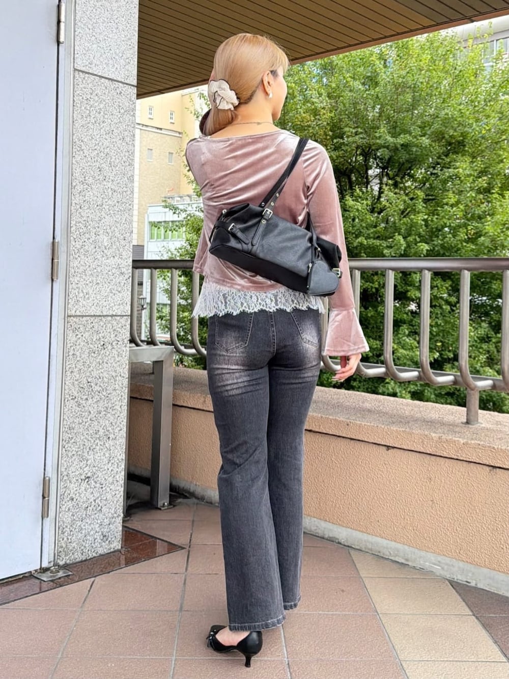 グレー系のデニムパンツ、ブラック系のパンプス、ブラック系のボストンバッグを着用したレディースの秋コーディネートの3枚目の写真