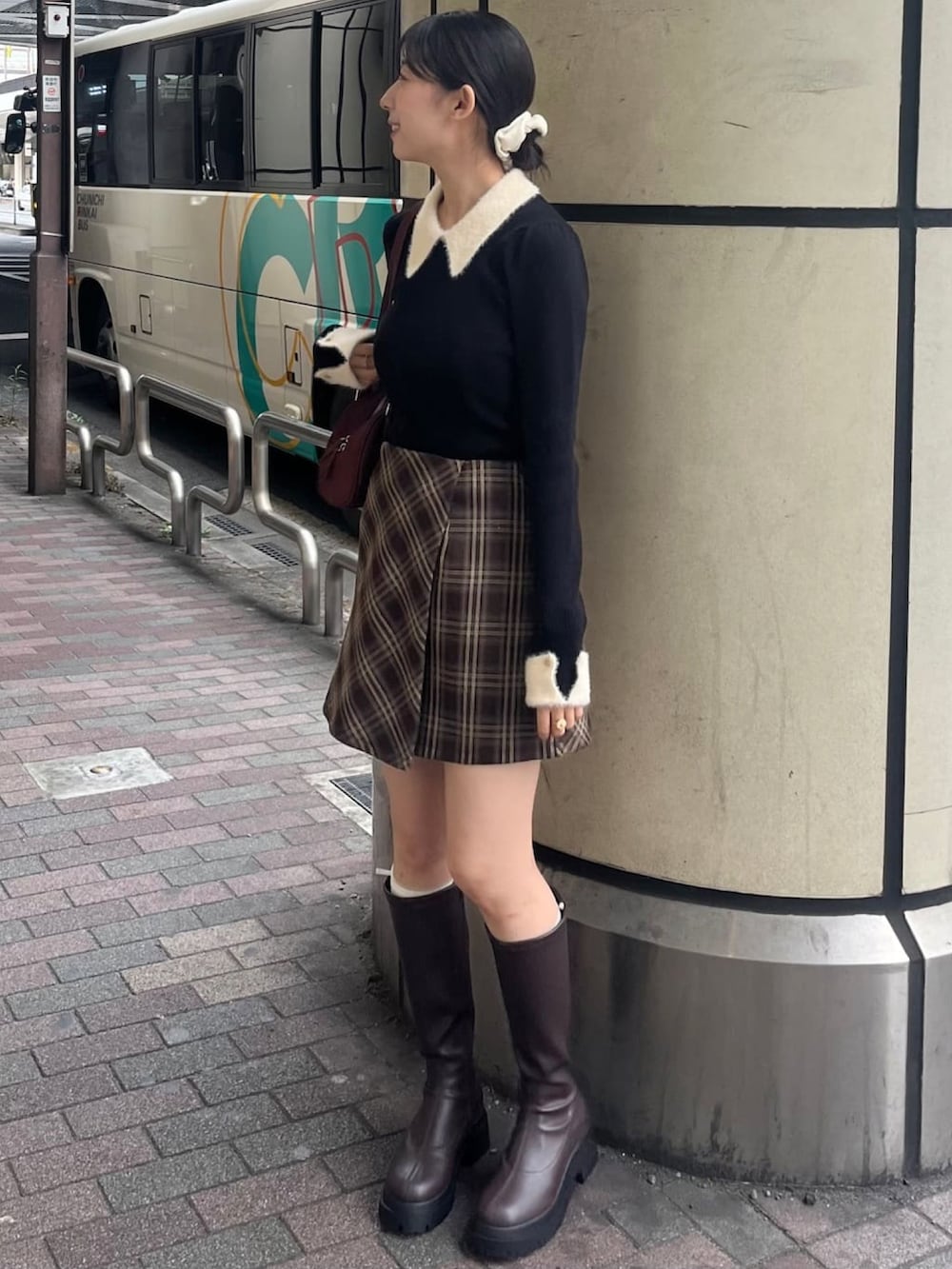 ブラック系のニット/セーター、ブラウン系のスカート、ブラウン系のブーツを着用したレディースの秋コーディネートの2枚目の写真