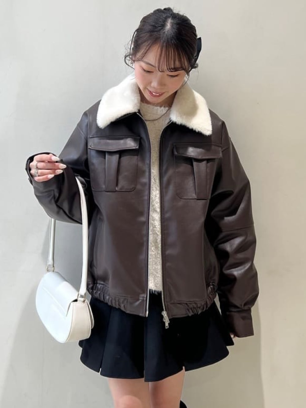 ブラウン系のブルゾン、ブラック系のスカート、ブラウン系のブーツを着用したレディースの冬コーディネートの3枚目の写真