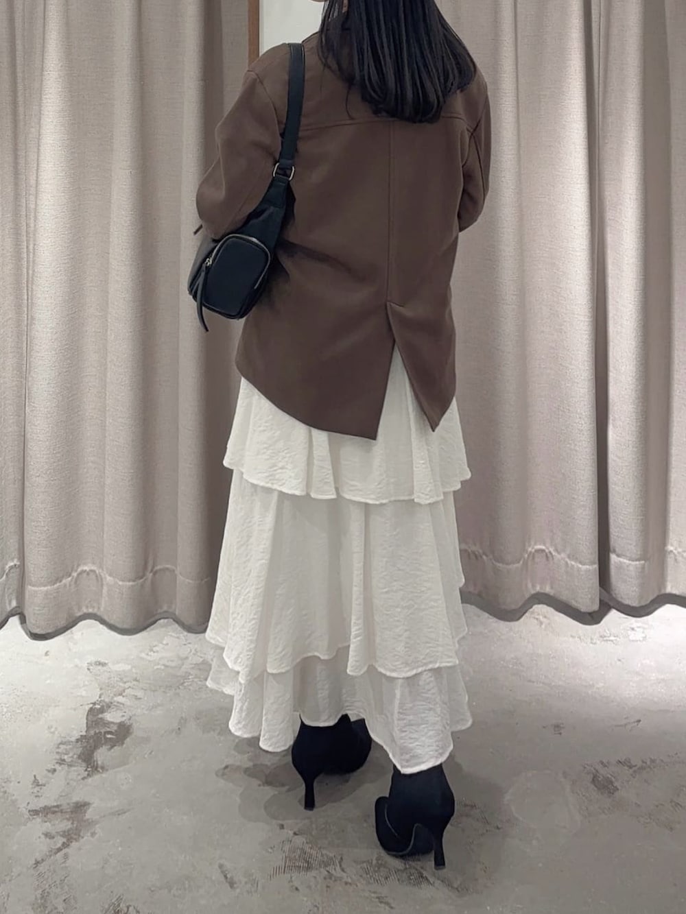 ブラウン系のテーラードジャケット、ブラック系のスカート、ブラック系のハンドバッグを着用したレディースの秋コーディネートの3枚目の写真