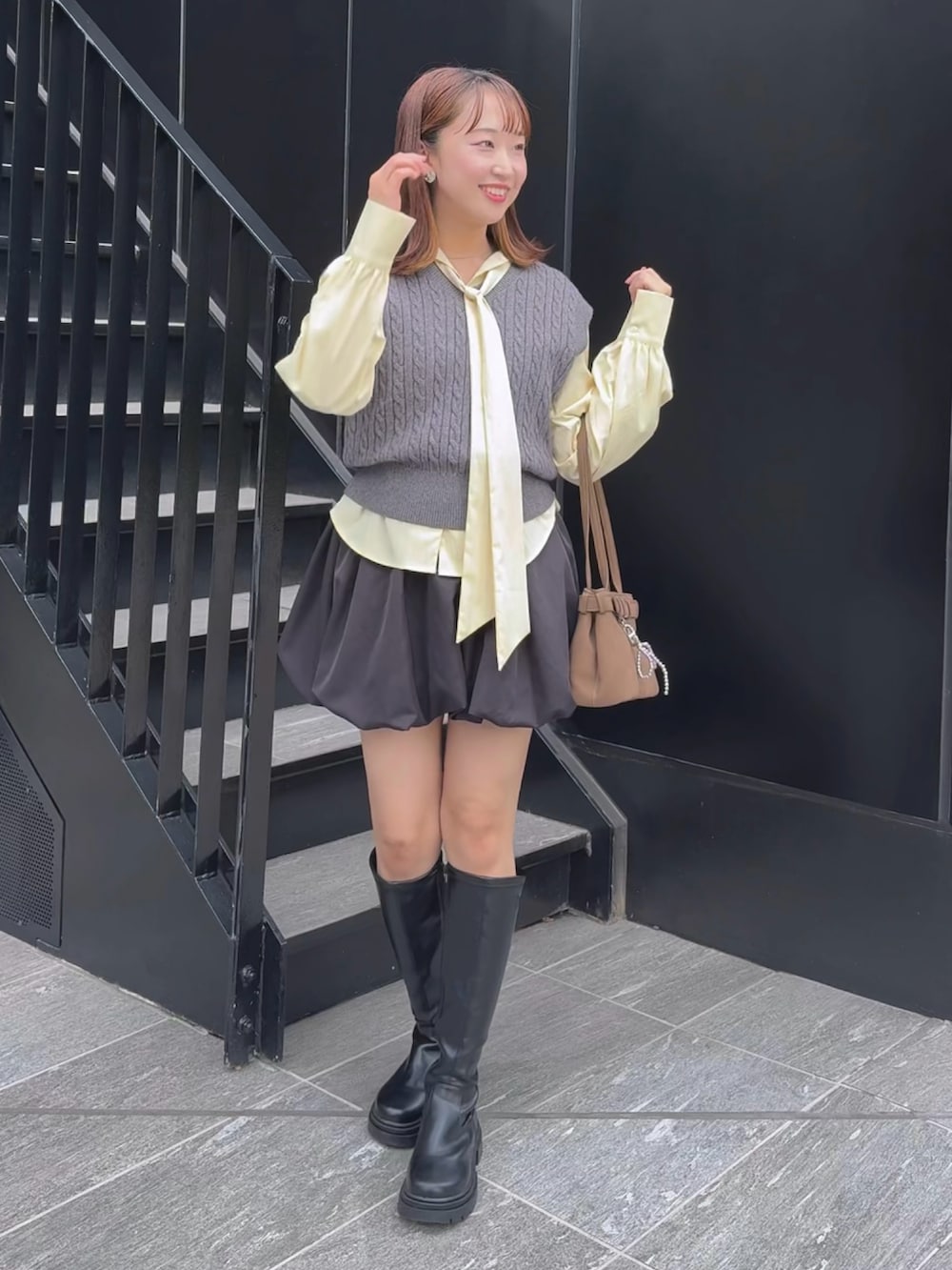 グレー系のニット/セーター、ブラック系のスカートを着用したレディースの秋コーディネートの2枚目の写真