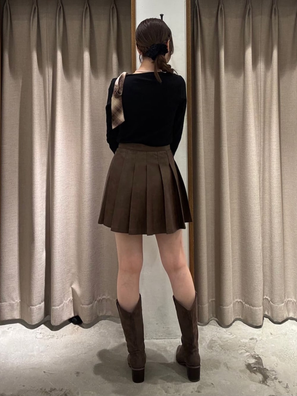 ブラック系のTシャツ/カットソー、ブラウン系のスカート、ブラウン系のブーツを着用したレディースの秋コーディネートの3枚目の写真