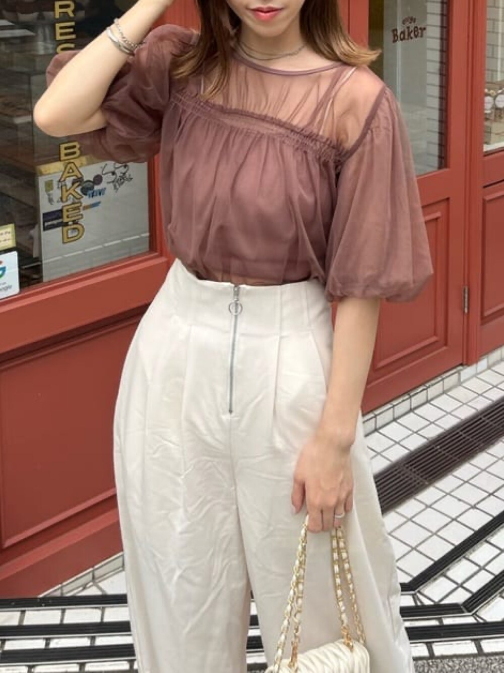 レッド系のTシャツ/カットソー、ホワイト系のスラックス、ホワイト系のショルダーバッグを着用したレディースの夏コーディネートの2枚目の写真