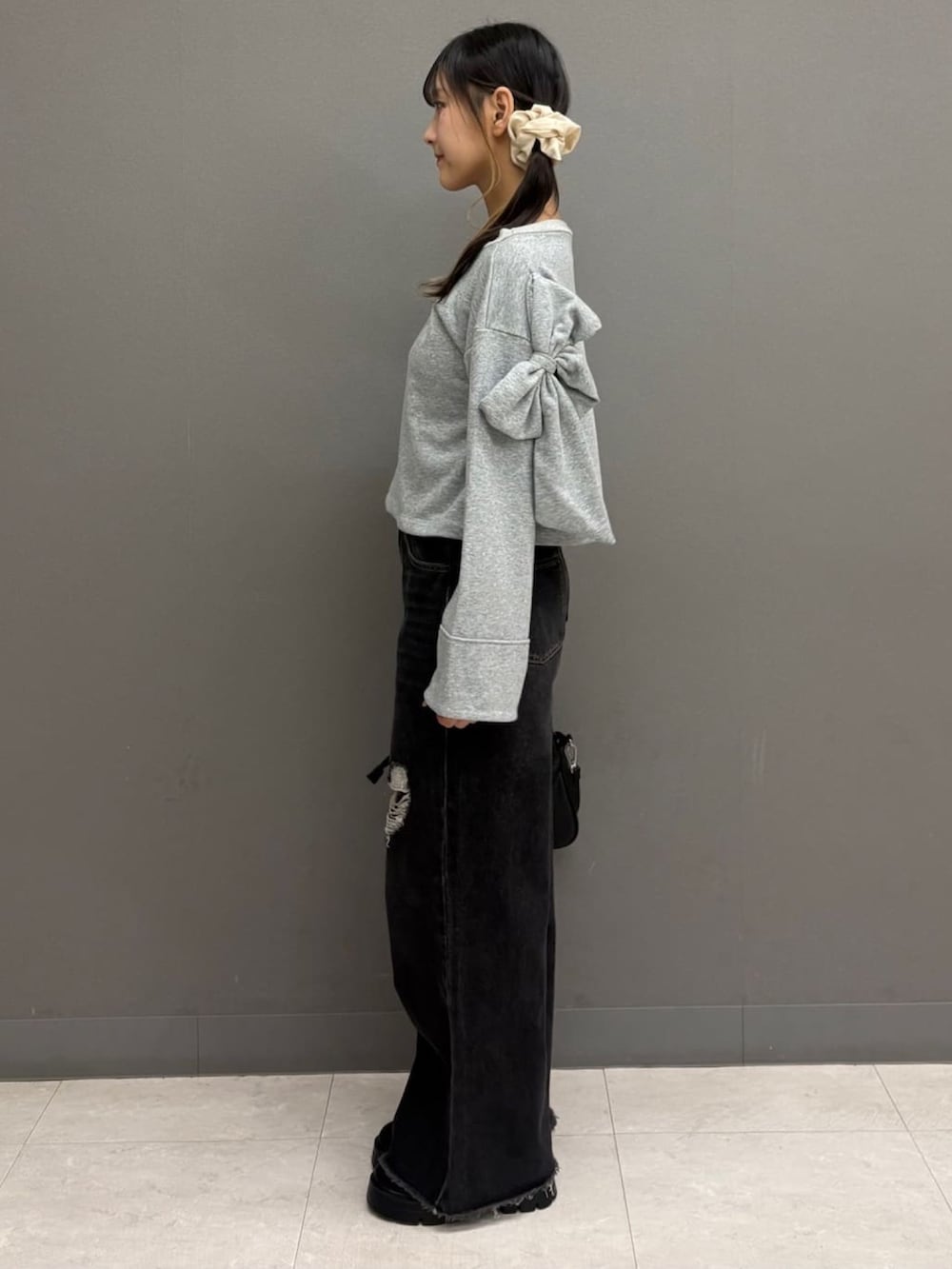 グレー系のTシャツ/カットソー、ブラック系のデニムパンツ、ブラック系のショルダーバッグを着用したレディースの秋コーディネートの2枚目の写真