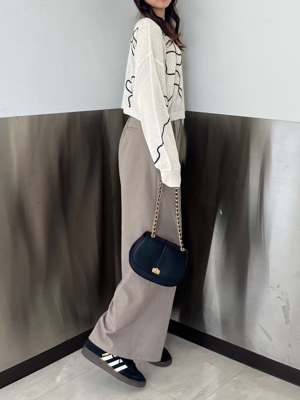 ホワイト系のカーディガン/ボレロ、ブラック系のショルダーバッグ、ブラウン系のスラックスを着用したレディースの春コーディネートの2枚目の写真