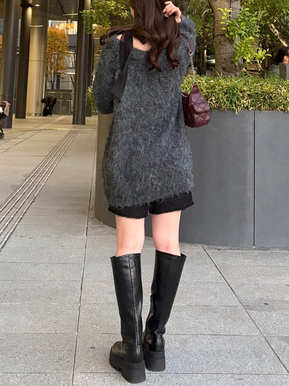 グレー系のチュニック、レッド系のショルダーバッグ、ブラック系のその他パンツを着用したレディースの冬コーディネートの3枚目の写真