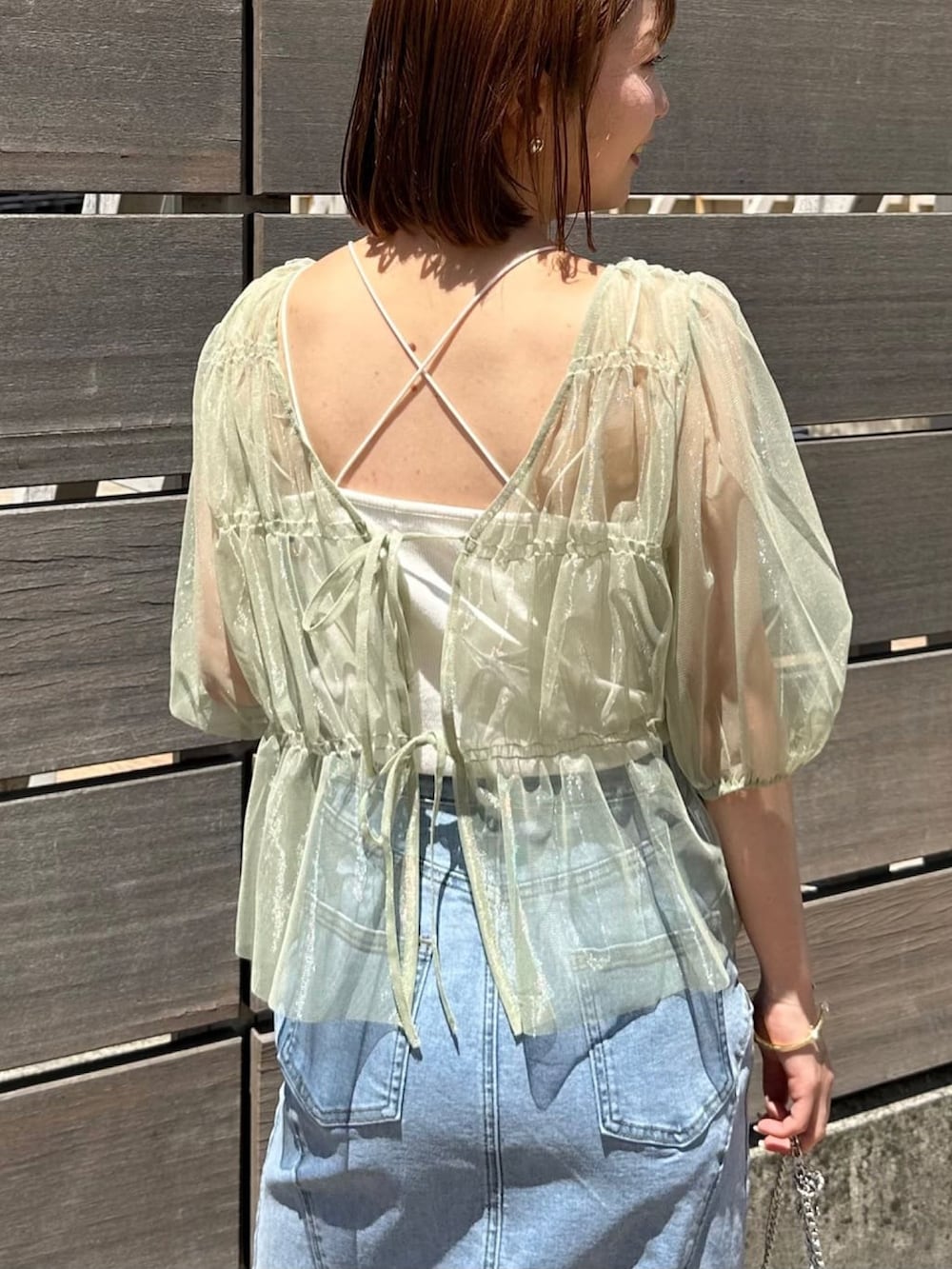 グリーン系のシャツ/ブラウス、ブルー系のデニムスカート、ブラック系のショルダーバッグを着用したレディースの夏コーディネートの2枚目の写真