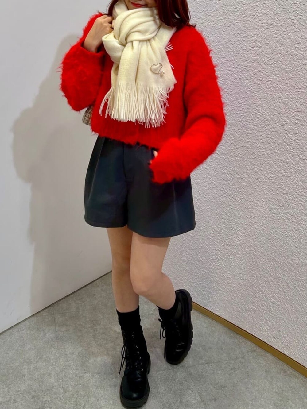 ブラック系のその他パンツ、レッド系のニット/セーター、ホワイト系のマフラーを着用したレディースの冬コーディネートの2枚目の写真