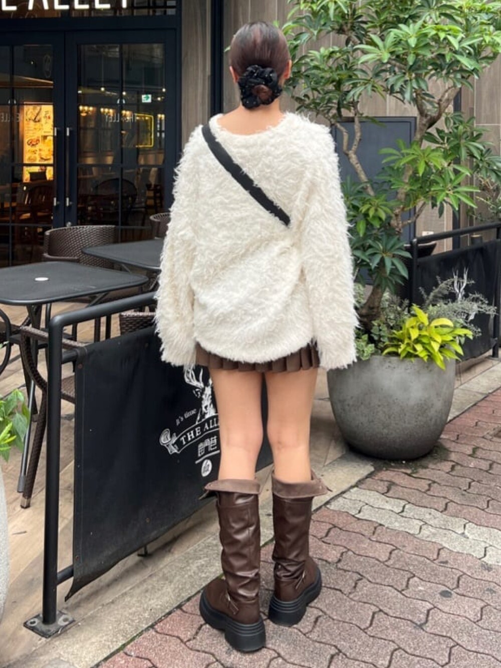 ベージュ系のカーディガン/ボレロ、ブラック系のショルダーバッグ、ブラウン系のブーツを着用したレディースの秋コーディネートの3枚目の写真