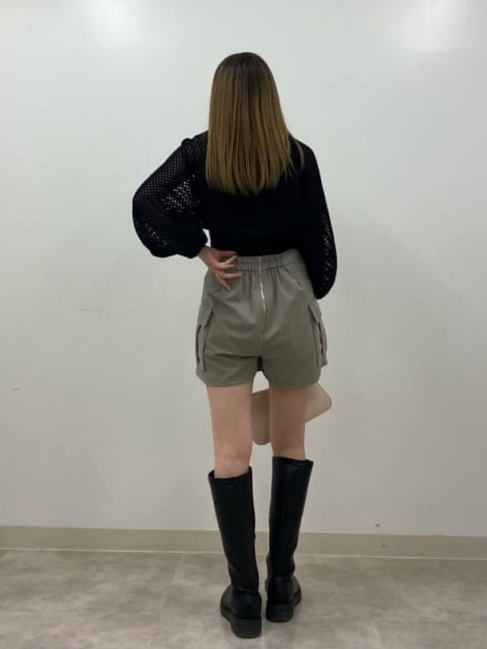 ブラック系のニット/セーター、ベージュ系のスカート、ホワイト系のハンドバッグを着用したレディースの冬コーディネートの2枚目の写真