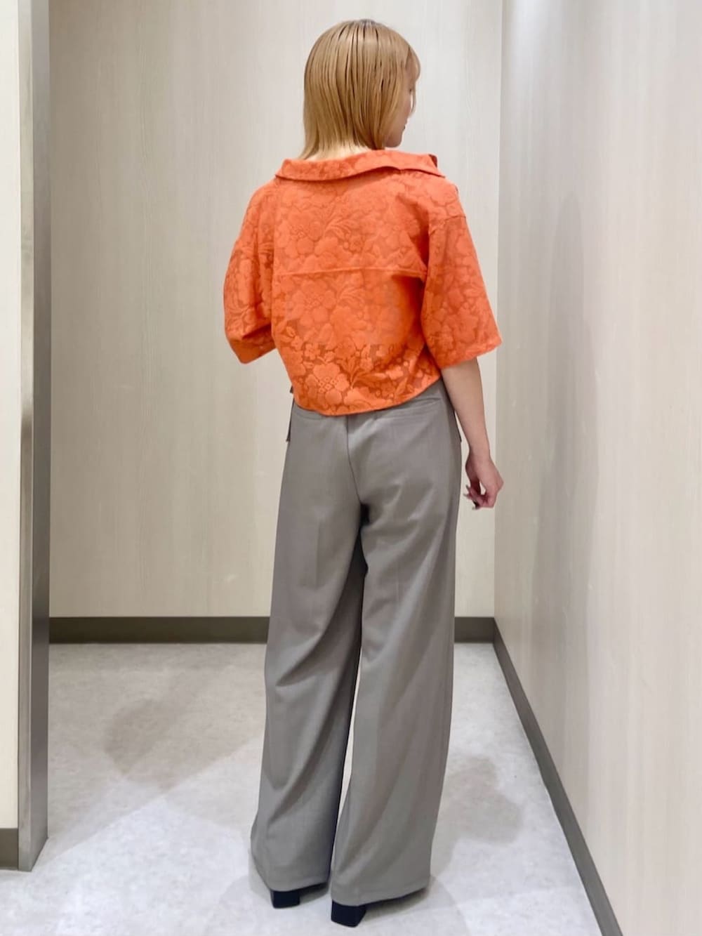 グレー系のスラックス、オレンジ系のシャツ/ブラウスを着用したレディースの夏コーディネートの2枚目の写真
