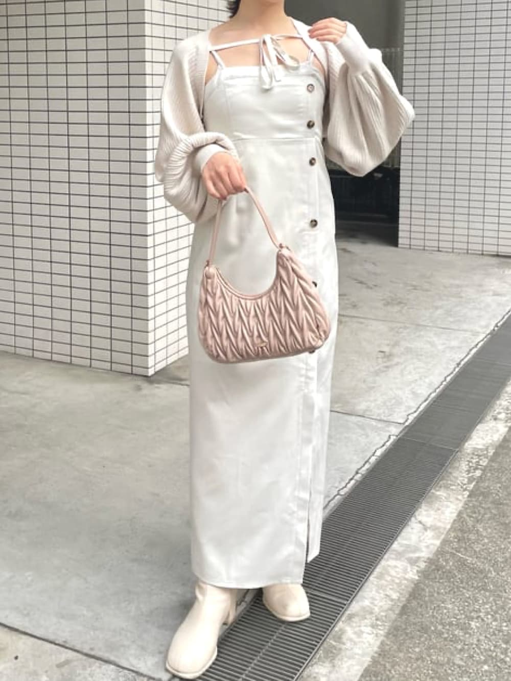 ホワイト系のワンピース、ピンク系のハンドバッグ、ホワイト系のカーディガン/ボレロを着用したレディースの冬コーディネートの2枚目の写真