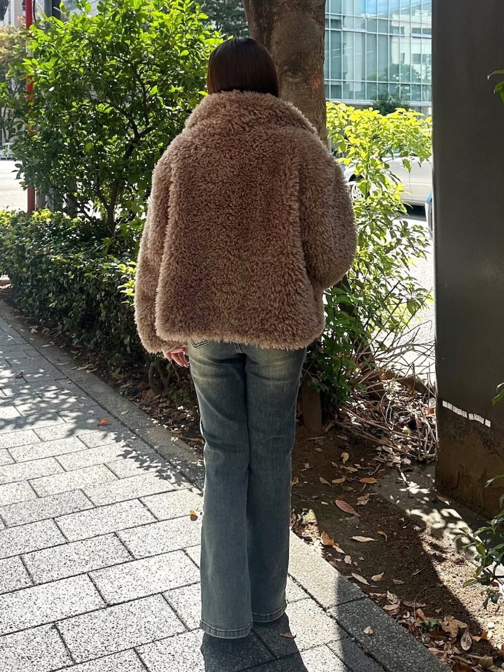 ブラウン系のブルゾン、ブルー系のデニムパンツ、ホワイト系のニット/セーターを着用したレディースの秋コーディネートの3枚目の写真