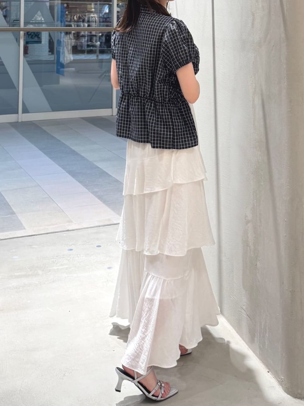ホワイト系のスカート、ブラック系のショルダーバッグ、グレー系のサンダルを着用したレディースの夏コーディネートの2枚目の写真