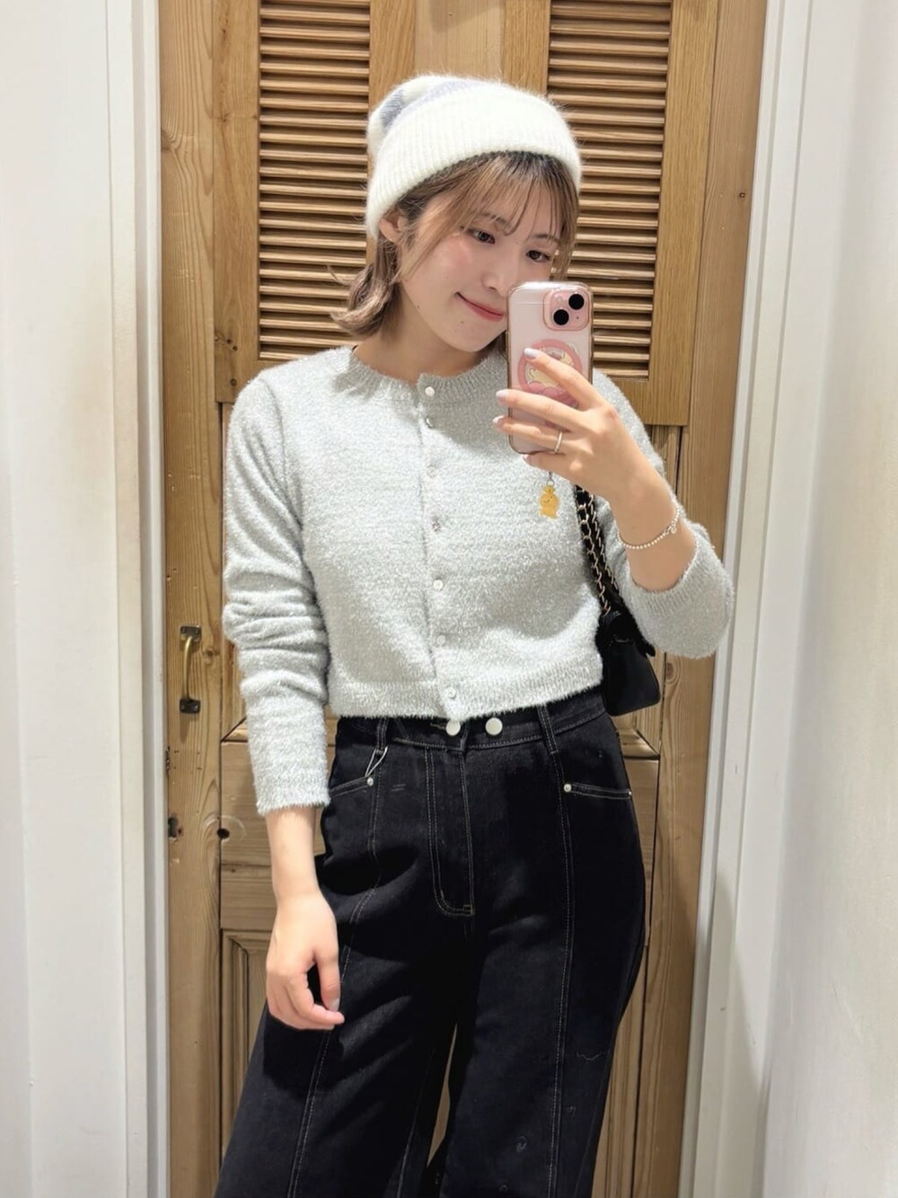 ブラック系のデニムパンツ、レッド系のショルダーバッグ、グレー系のニット/セーターを着用したレディースの冬コーディネートの2枚目の写真