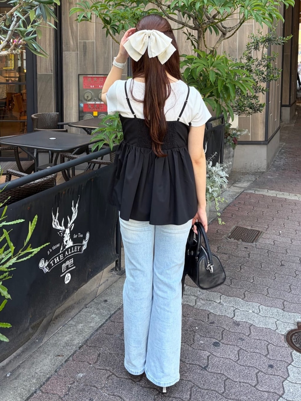 ブラック系のシャツ/ブラウス、ホワイト系のTシャツ/カットソー、ブルー系のデニムパンツを着用したレディースの夏コーディネートの3枚目の写真