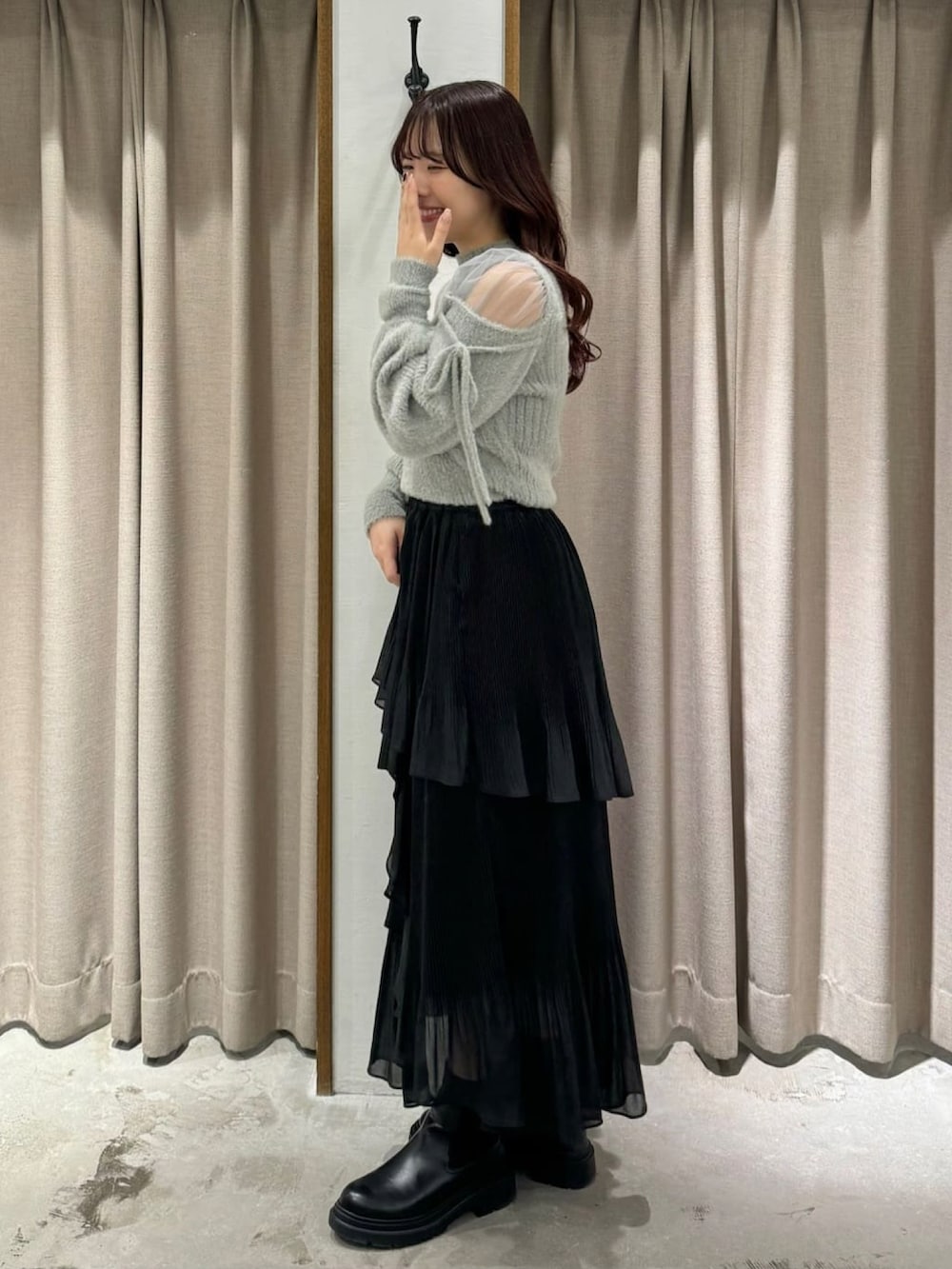 グレー系のニット/セーター、ブラック系のスカート、ブラック系のブーツを着用したレディースの冬コーディネートの2枚目の写真