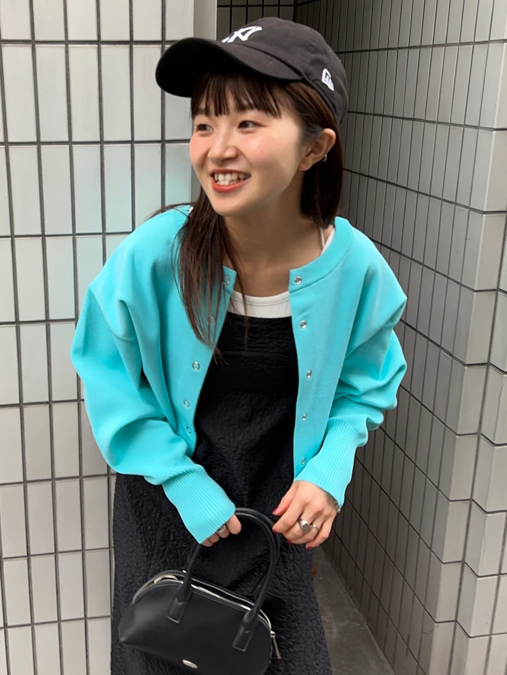 ブラック系のワンピース、ブラック系のボストンバッグ、ブルー系のカーディガン/ボレロを着用したレディースの冬コーディネートの2枚目の写真