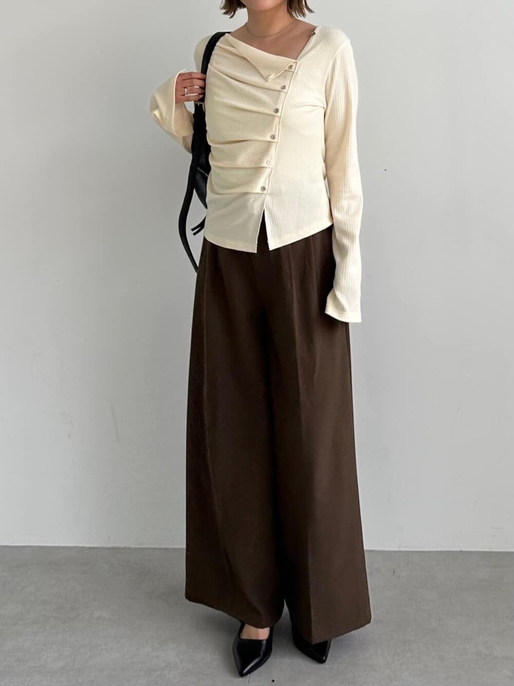 ホワイト系のTシャツ/カットソー、ブラウン系のスラックス、ブラック系のパンプスを着用したレディースの秋コーディネートの2枚目の写真