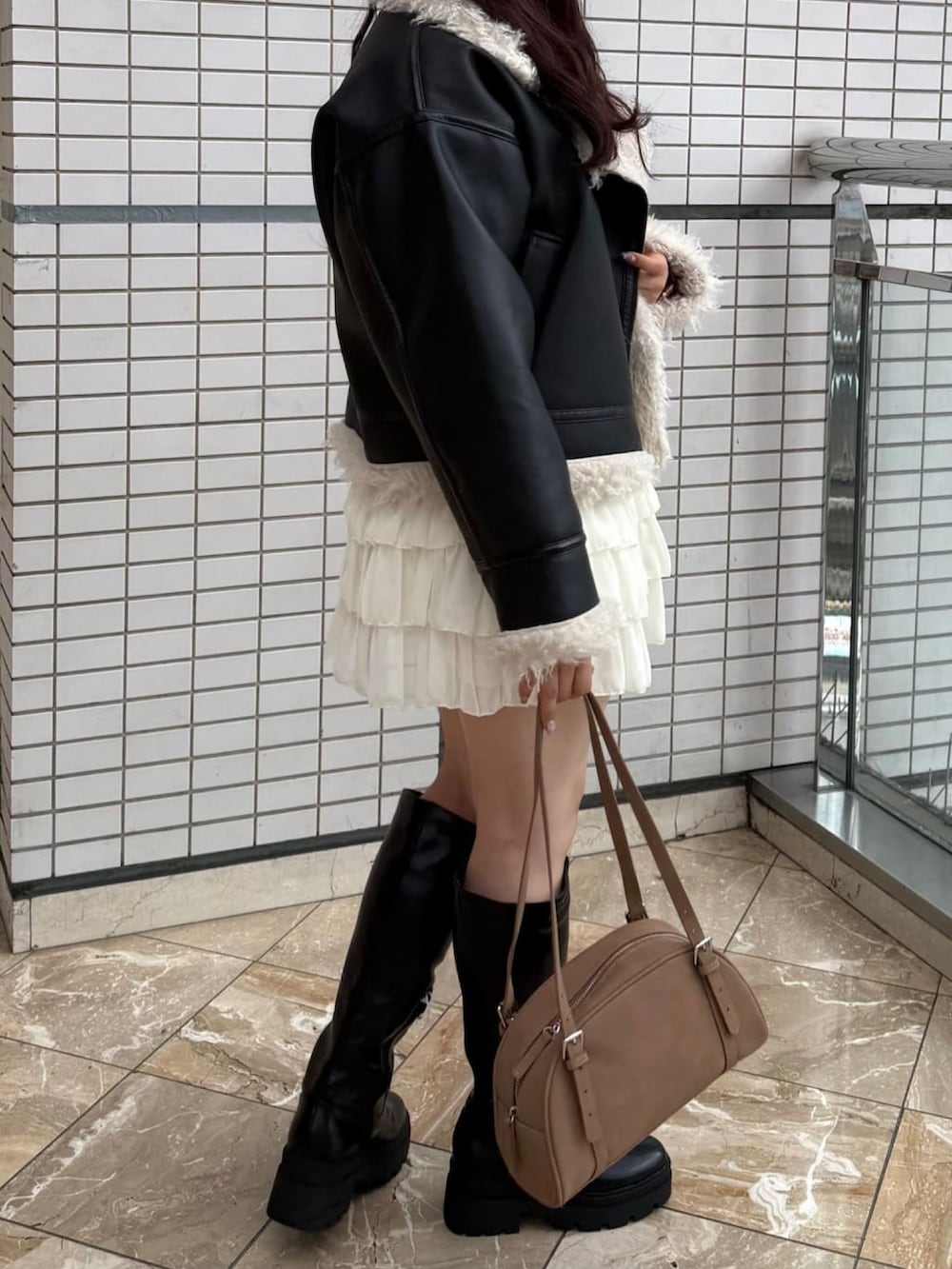 ブラック系のムートンコート、ホワイト系のスカートを着用したレディースの秋コーディネートの2枚目の写真