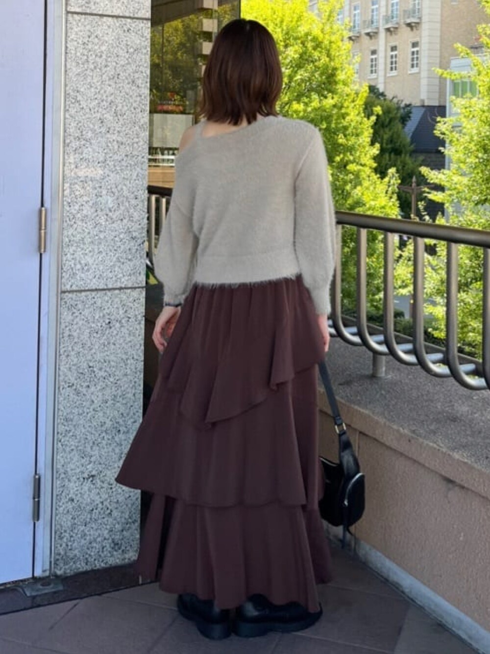 ベージュ系のニット/セーター、ブラウン系のスカート、ブラック系のハンドバッグを着用したレディースの秋コーディネートの2枚目の写真