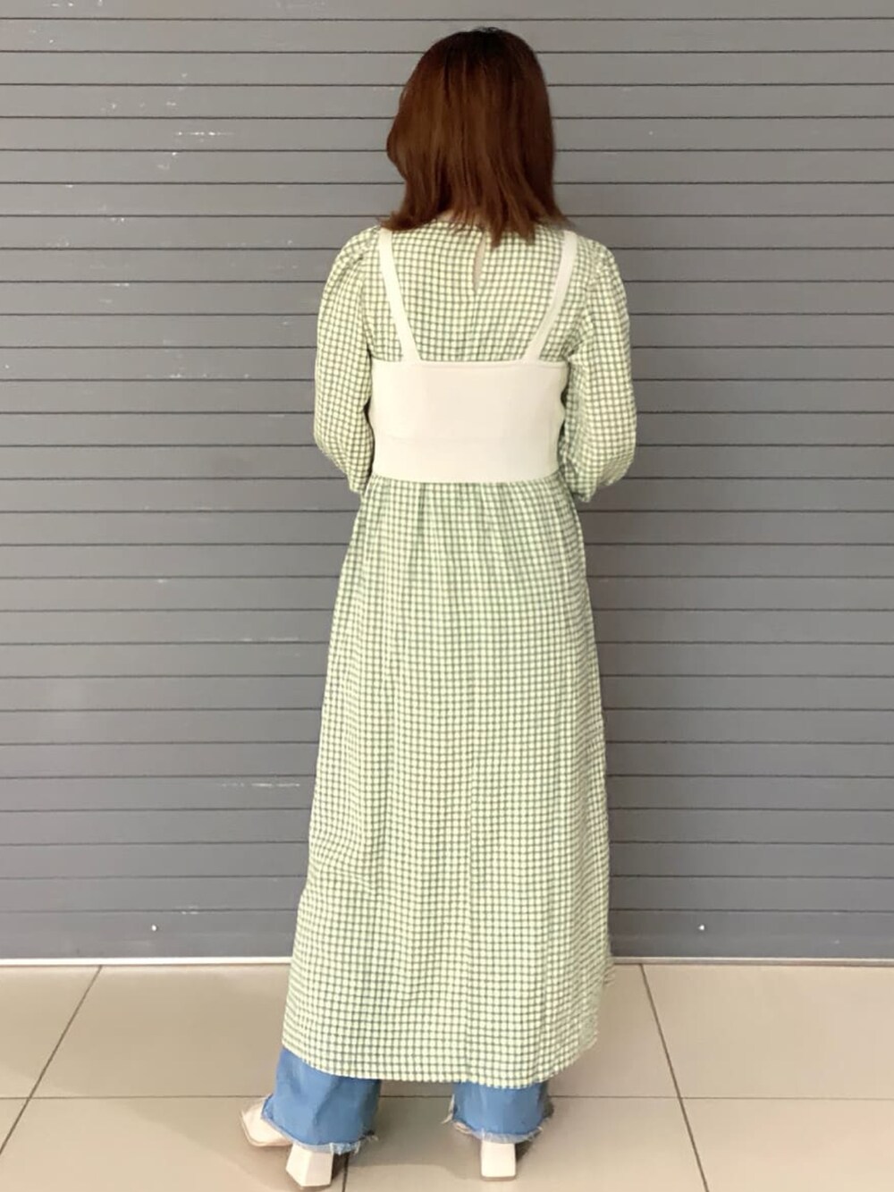 グリーン系のワンピース、ホワイト系のブーツを着用したレディースの春コーディネートの2枚目の写真