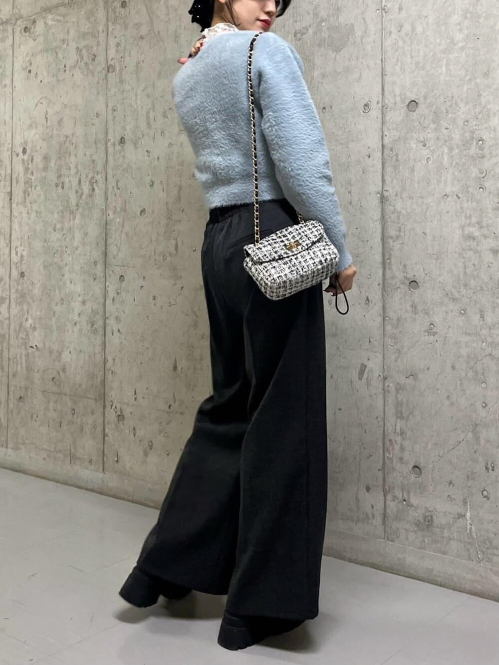 ブルー系のニット/セーター、ブラック系のスラックス、グレー系のショルダーバッグを着用したレディースの冬コーディネートの2枚目の写真