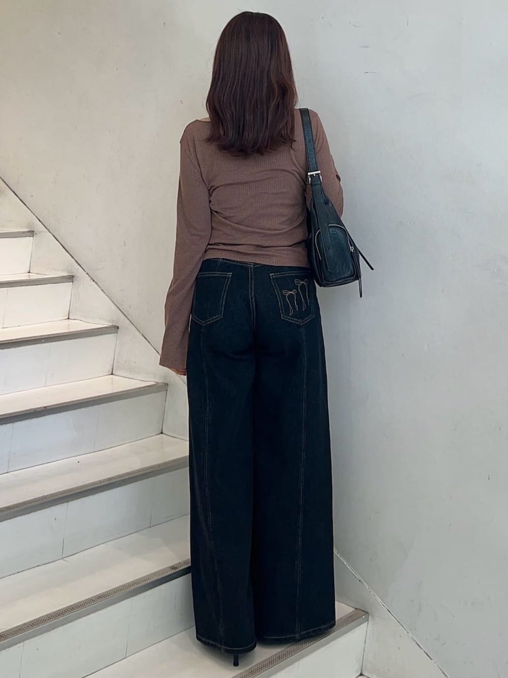 ブラウン系のTシャツ/カットソー、ブラック系のデニムパンツ、ブラック系のハンドバッグを着用したレディースの秋コーディネートの2枚目の写真