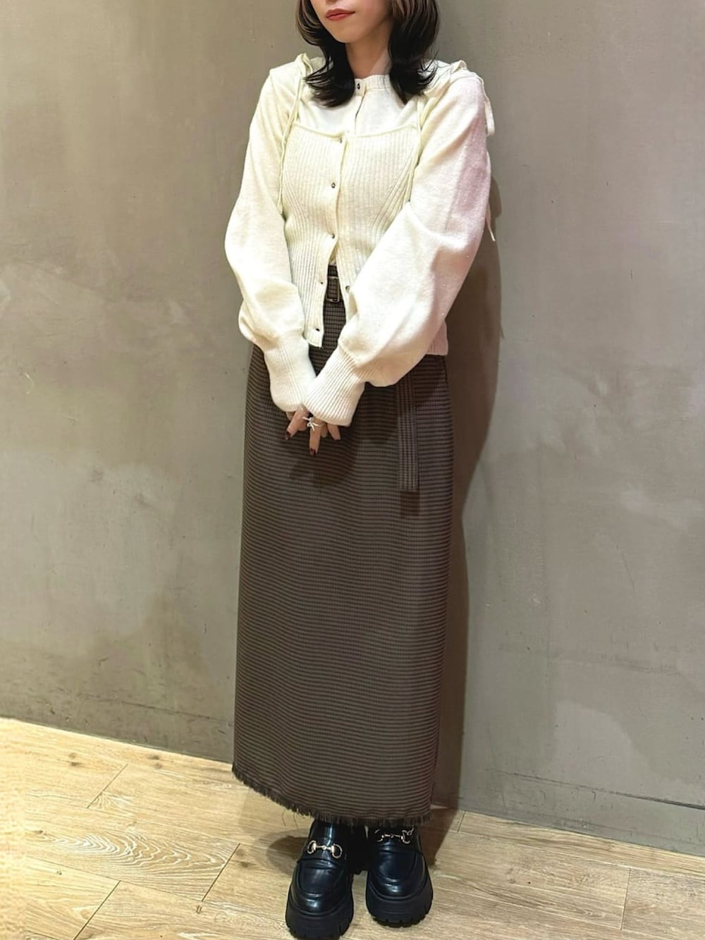 ホワイト系のニット/セーター、オレンジ系のスカート、ブラック系のローファーを着用したレディースの冬コーディネートの2枚目の写真