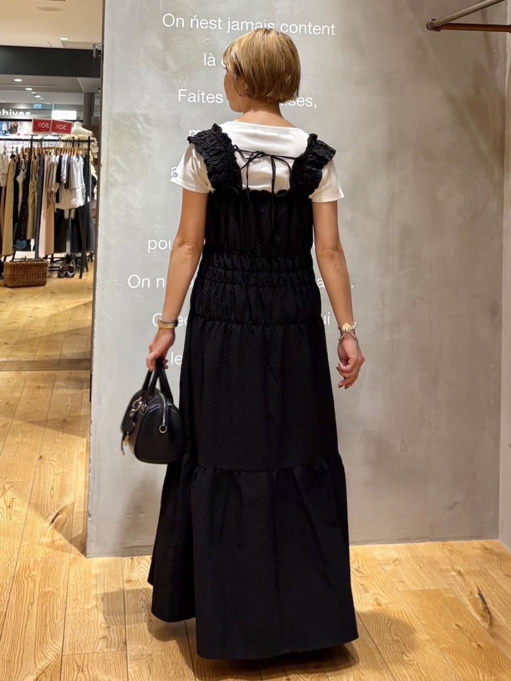 ブラック系のワンピース、ブラック系のボストンバッグ、ブラウン系のサンダルを着用したレディースの夏コーディネートの3枚目の写真