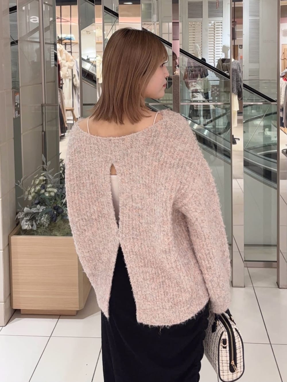 ピンク系のニット/セーター、ブラック系のスカート、ホワイト系のボストンバッグを着用したレディースの冬コーディネートの3枚目の写真