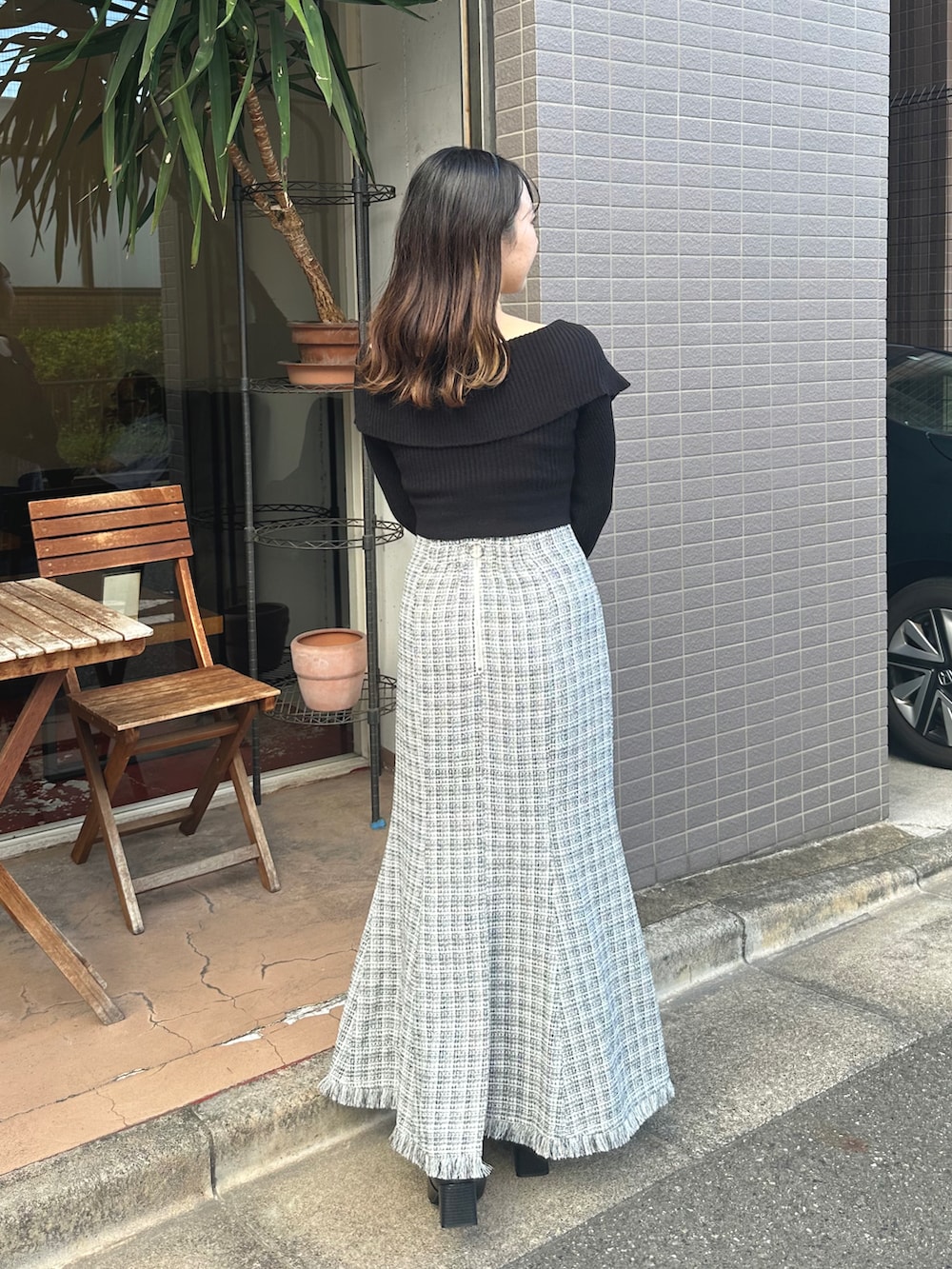 ブラック系のニット/セーター、ホワイト系のスカートを着用したレディースの秋コーディネートの2枚目の写真