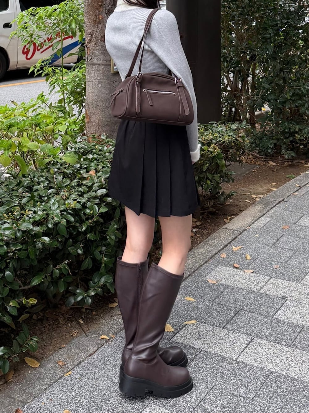 ブラック系のニット/セーター、ブラック系のスカート、ブラウン系のボストンバッグを着用したレディースの秋コーディネートの2枚目の写真