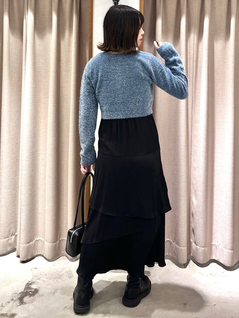 ブルー系のニット/セーター、ブラック系のスカートを着用したレディースの冬コーディネートの2枚目の写真