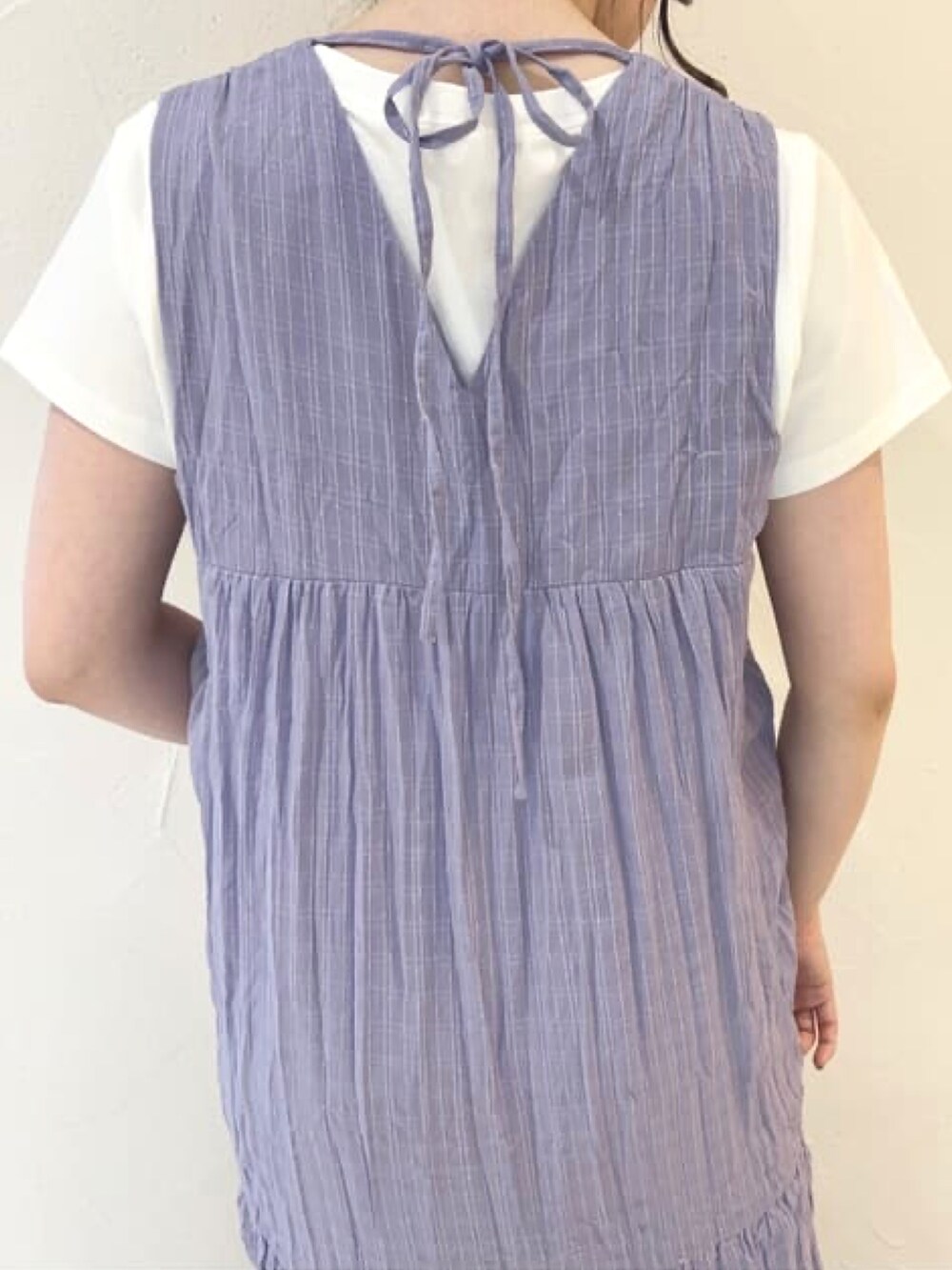 パープル系のワンピース、ホワイト系のTシャツ/カットソー、ブラック系のサンダルを着用したレディースの夏コーディネートの4枚目の写真